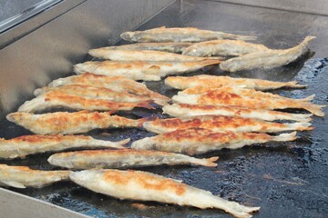 Preparing fish on a flat grill with oil. Outdoor seafood barbecue cooking. Picnic on backyard at open air. Street food festival. Pescetarian diet. Healthy ingredients