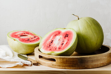 Pink watermelon cut in half on a wooden tray.