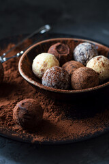Truffle candies in cocoa on a plate on a dark background. Assorted chocolate truffles. Close.