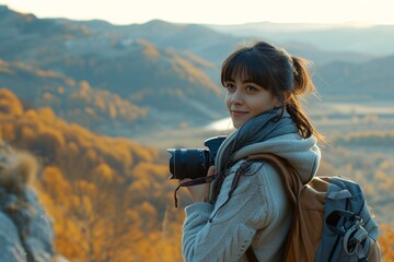 Obraz premium A girl, photographer is enjoying the view from a top of a mountain and holding a camera