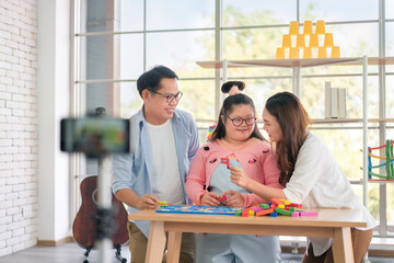 Happy asian father and mother playing education toy with their daughter down syndrome child, As...