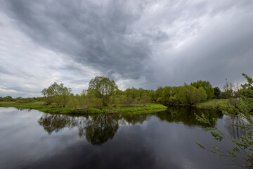 Dramatic sky against the background of a spring landscape by the river