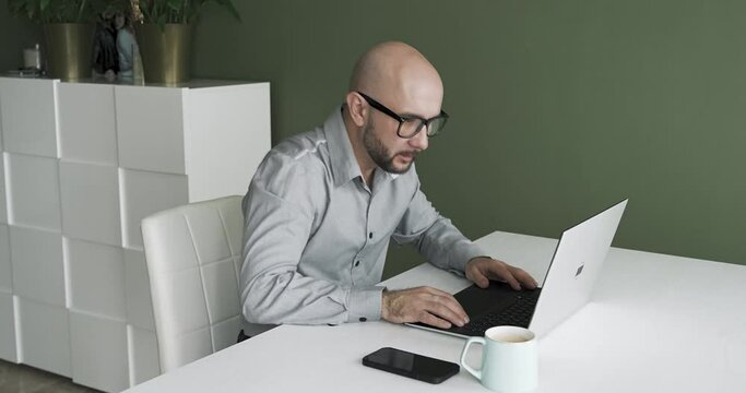A man with glasses works from home on a laptop in his office having different emotions. concertation 