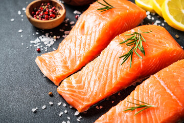 Salmon fillet, raw fresh fish with rosemary and spices at black background.