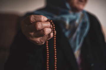 The old Muslim grandmother holds the rosary in her hands.