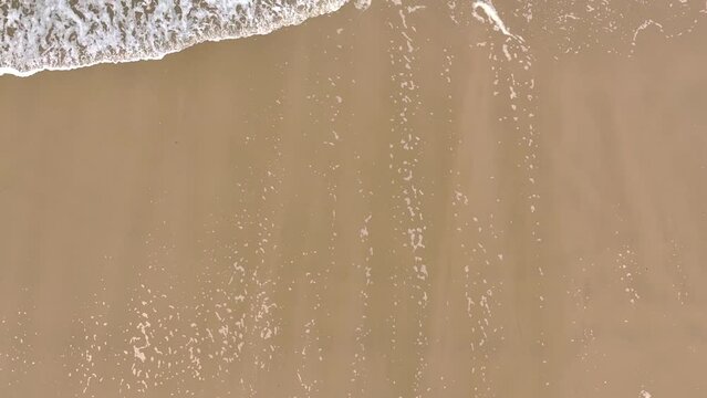Drone slow-motion over foamy ocean waves washing sand of tropical beach at the daytime