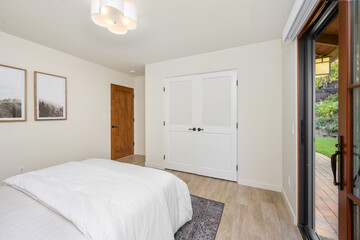 a bedroom with two pictures hung above the bed and sliding glass doors to an outside