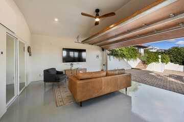 a large patio features a couch, tv and sliding glass door