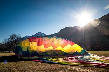 Deflating hot air balloon with a beautiful backdrop - the sun rising in In Valle d'Aosta, Italy.
