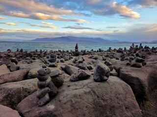 piles of rocks near the sea on a beach at sunset