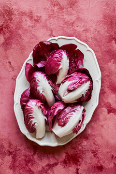 Raddichio leaves on oval white plate on pink background