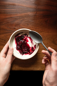 Bowl of yoghurt and blackberry compot on antinque wooden table with silver spoon.