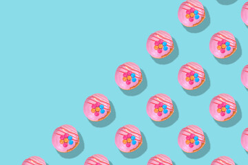 Modern retro color theme pattern of pink donuts against an aqua blue background with negative copy space.