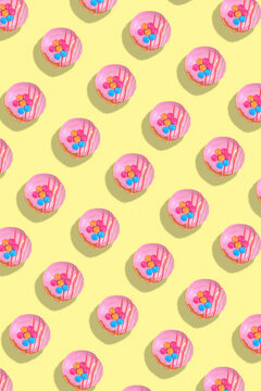 Modern retro color theme pattern of pink donuts against a yellow background.