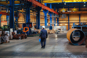 Industrial worker walking at pipe factory