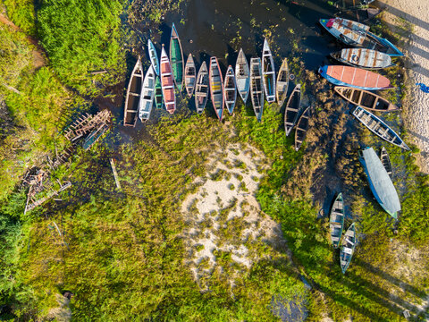 Aerial drone view of canoes and small boats resting on the dry riverbed in the Amazon region during the dry season.