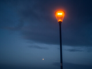 Modern powerful LED light in old style lantern against blue cloudy sunset sky. City and town...