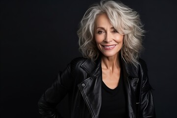 Portrait of a beautiful senior woman in a leather jacket on a dark background