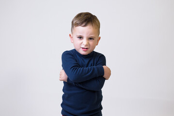 Portrait of an upset cute little kid standing with arms folded and looking at camera isolated over white background