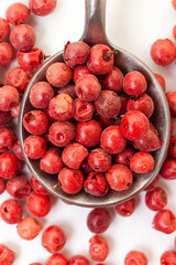Red peppercorns in iron spoon on white background. Organic spice. Dry red pepper grain.