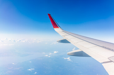 View from the airplane window at a beautiful cloudy sky and the airplane wing