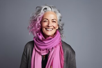Portrait of a happy senior woman with pink scarf over grey background