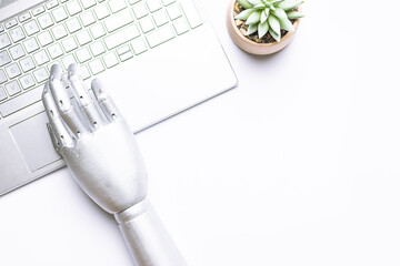 Artificial intelligence concept. Metal robotic hand working with lap top keyboard on white...