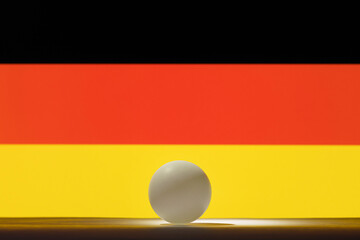 The pingpong ball stands on a surface in front of Germany flag.