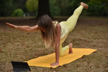 Foto op Plexiglas A middle-aged woman is doing yoga in the park © Natalje Dietrich