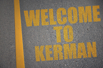 asphalt road with text welcome to Kerman near yellow line.