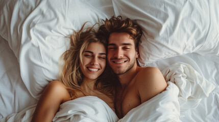 Young beautiful and loving couple wake up while lying under the covers on soft white bed at the morning.