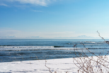 海岸から望む冬の海と対岸の山 - obrazy, fototapety, plakaty