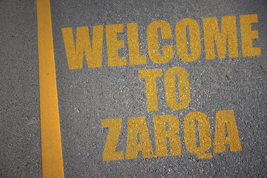 asphalt road with text welcome to Zarqa near yellow line.