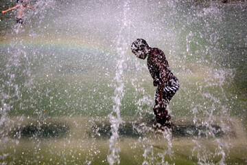 kid cooling off on the fountain in the park trocadero. Paris, France - obrazy, fototapety, plakaty