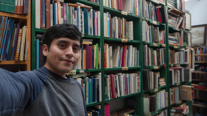 Young man in library holding secondhand books, with space for text