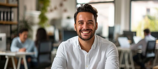 A man in a white dress shirt is happily smiling, showing his pearly whites, in an office building, sharing a joyful gesture during a fun event. - obrazy, fototapety, plakaty