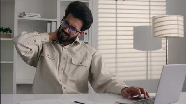 Arabian Indian businessman programmer employee working laptop at office desk male suffer neck pain backache discomfort computer work unhealthy sick business man massage back spine muscles health care