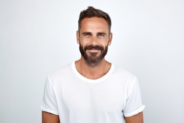 Handsome young man in white t-shirt looking at camera and smiling while standing against grey background
