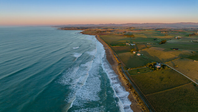 Aerial: Ocean beach and farmalnd at sunrise. Oamaru, Otago, New Zealand.