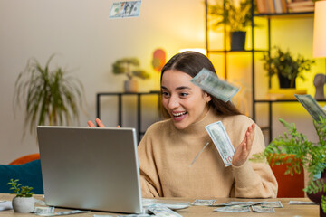 Money cash dollar rain falling on Caucasian young woman use laptop celebrating success play winning...