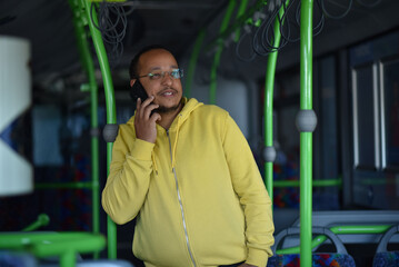 a lustful dark-skinned young man is sitting in the bus and talking on the phone