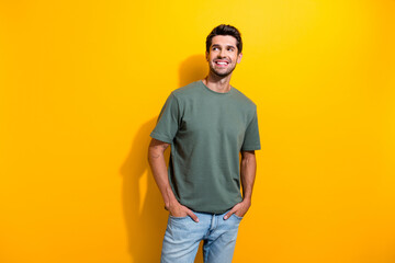 Portrait of pleasant positive guy wear stylish t-shirt plams in pockets look at promo empty space...