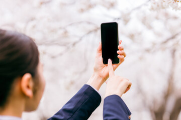 スマホで桜の写真を撮る中学生・高校生・女子高生・女子高校生
