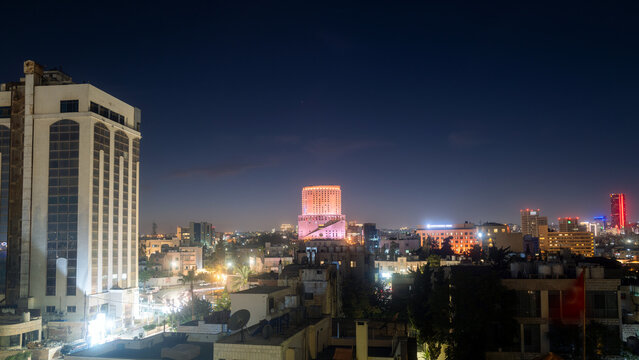 Amman, Jordan - October 9 2022 : Le Royal luxury hotel tower, one of the tallest buildings in the capital city, lit up at night with skyline. Editorial background wallpaper
