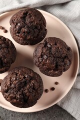 Delicious chocolate muffins on grey textured table, top view