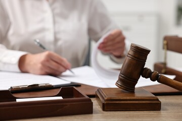 Lawyer working with documents at wooden table in office, focus on gavel