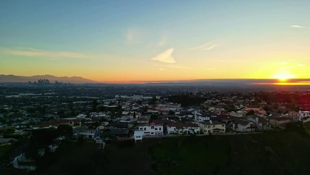Aerial drone shot of sun rising over houses in Kenneth Hahn Recreational Area during morning time in Los Angeles, CA, USA.