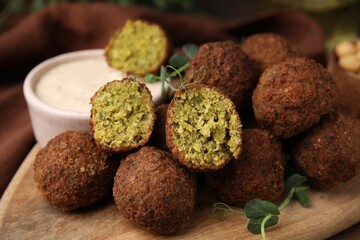 Delicious falafel balls and sauce on table, closeup