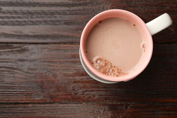 Tasty hot chocolate on wooden table, top view. Space for text
