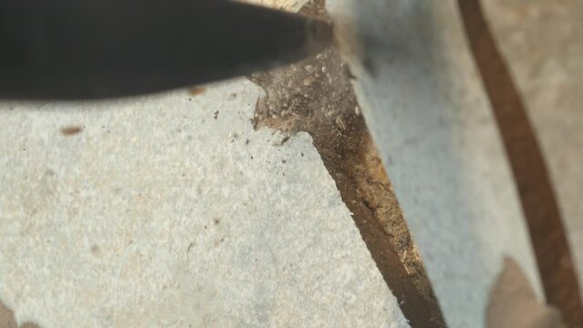 slow motion video of a pointed hammer hitting a wooden surface, which breaks apart.